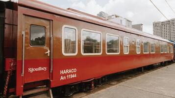 Un wagon de train ancien, portant les inscriptions « HARACO An 11944 » et « Sjourney », est garé sur des voies ferrées, avec des bâtiments en arrière-plan.