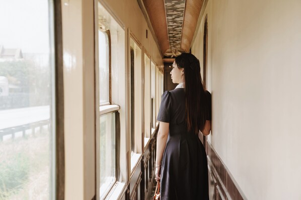 A person standing by a train window, looking outside. - SJourney Luxury Train -Southbound Legacy (Hanoi)