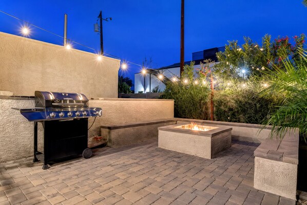 An outdoor patio with a barbecue grill and a fire pit.