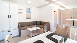 A modern, well-lit room with a sofa, a small table, and a dining area. - Dream Holiday on the Water in Portoroz (Piran)