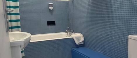 A bathroom with a bathtub, toilet, and sink.