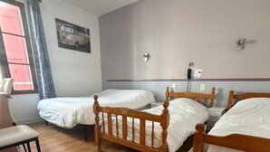 A room with three wooden beds, a chair, and a window with curtains. - Hôtel du Commerce (Millau)