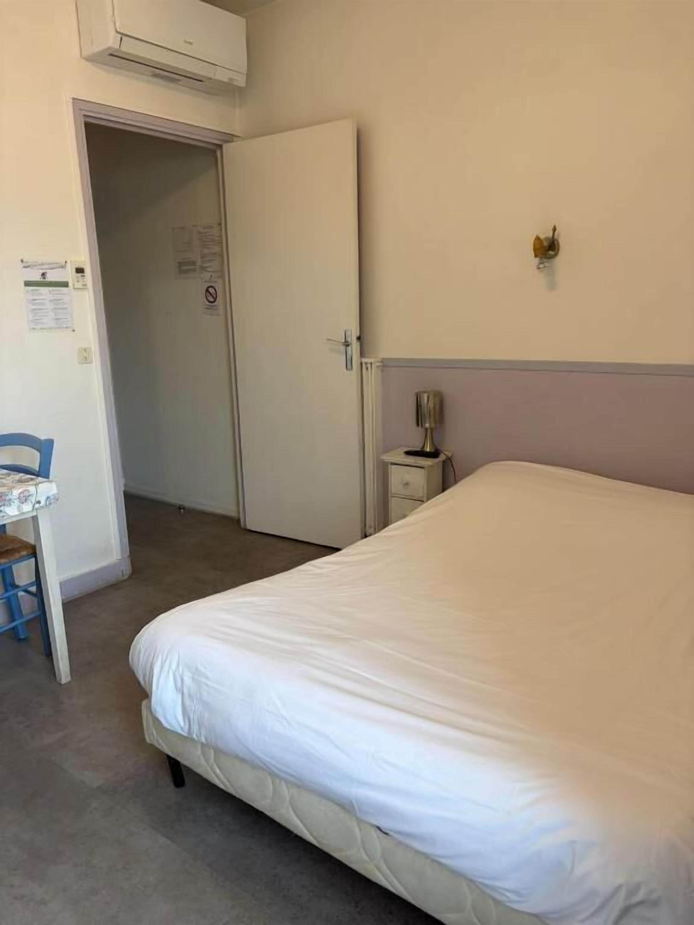 Un dormitorio con una cama, un escritorio, una silla, una mesita de noche y una lámpara de pared.
