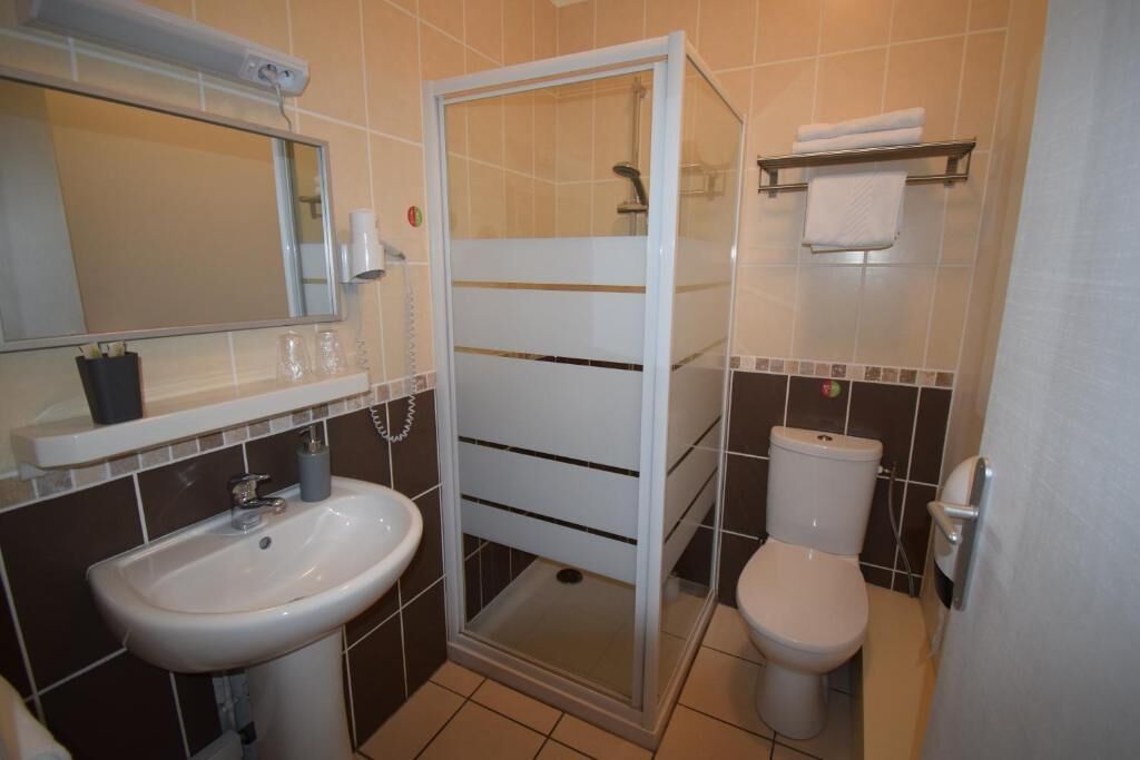 Ein Badezimmer mit Duschkabine, Waschbecken, Toilette und Spiegel.