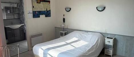 A bedroom with a bed, bedside tables, a radiator, and a window.