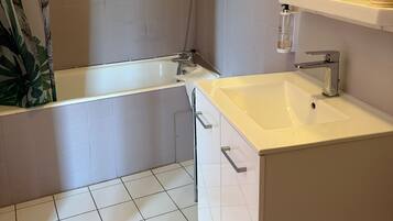 A bathroom with a bathtub, a sink, and a mirror.