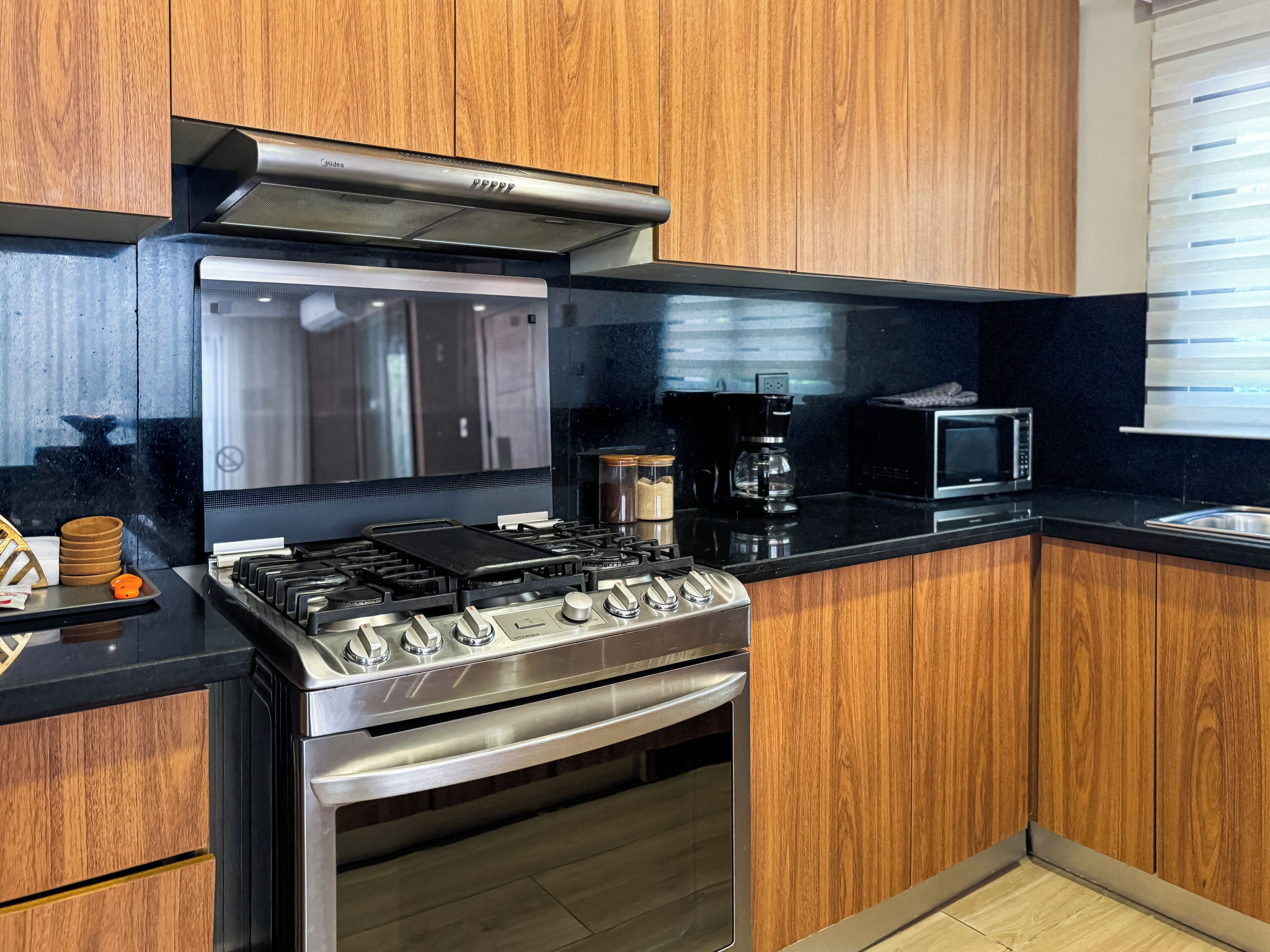 A kitchen with a gas stove, oven, microwave, and wooden cabinets.