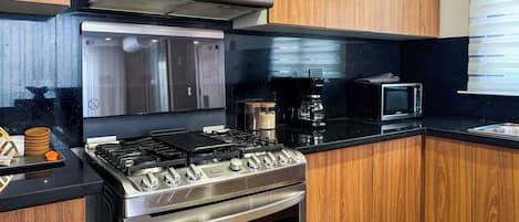 A kitchen with a gas stove, oven, microwave, and wooden cabinets.