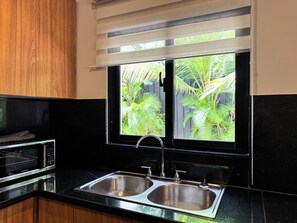 Eine Küche mit einem doppelten Spülbecken, einer Mikrowelle und einem Fenster mit Jalousien.
