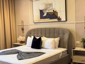 Ein Hotelzimmer mit einem großen Bett, einem Nachttisch, einer Wandmalerei und einem Vorhang.