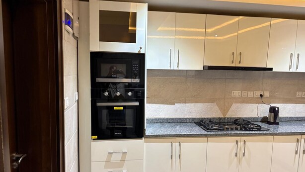 A modern kitchen with a built-in oven, microwave, and gas stove. - Luxury stylish premium Home in Prime Location, Exceptional Hospitality (Abuja)