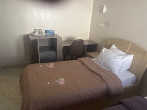 Une chambre d’hôtel standard, équipée d’un lit, d’un bureau et d’une chaise.