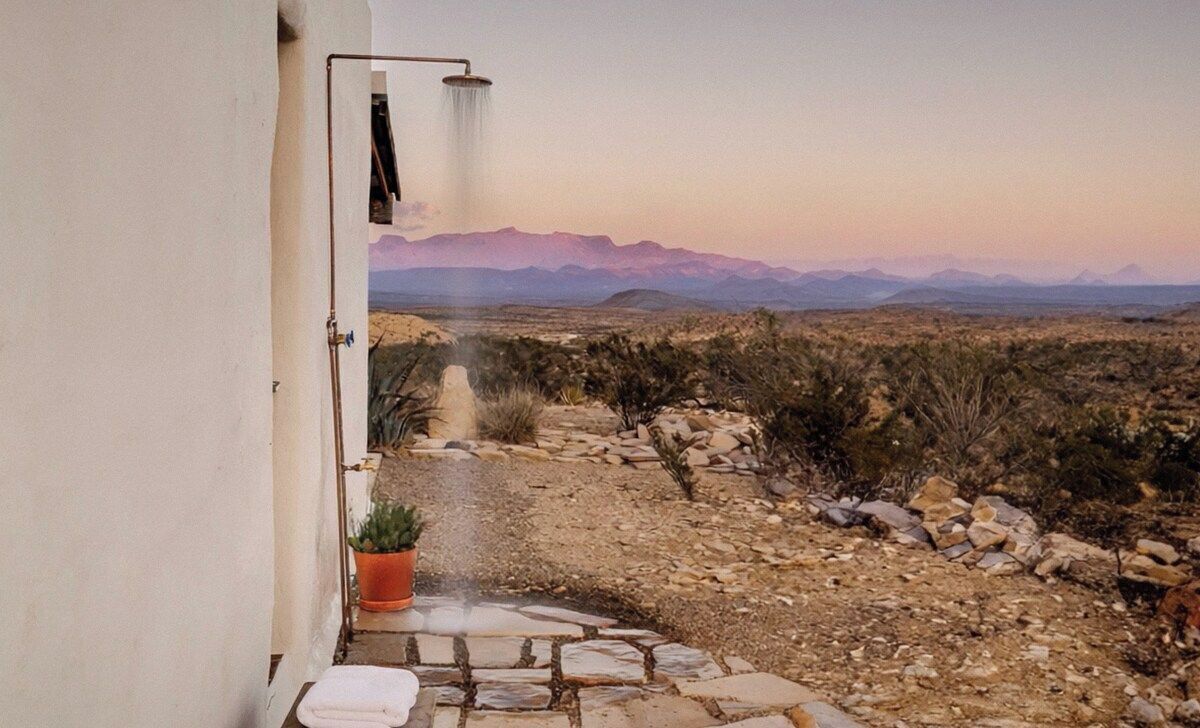 A doorway leading to a desert landscape with mountains in the distance.