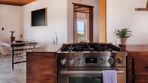 Een moderne keuken met een Bosch gasfornuis, oven, en een eethoek met een tafel en stoelen.