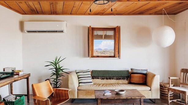 Een gezellige woonkamer met houten plafond, een bank, een salontafel en een raam met uitzicht.