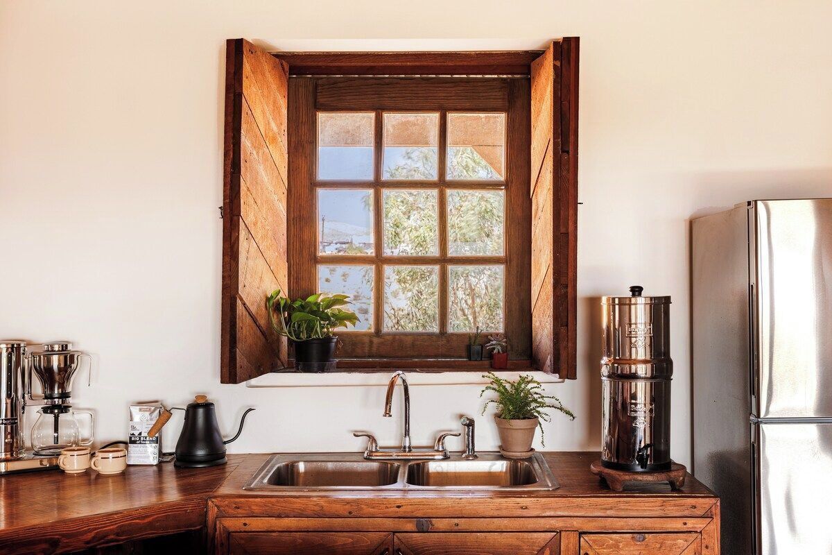 A kitchen with a wooden window, stainless steel appliances, and a coffee maker.