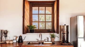 A kitchen with a wooden window, stainless steel appliances, and a coffee maker.