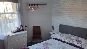 Un dormitorio con cama, una silla, un escritorio y una ventana.