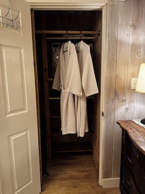 Een hal met een houten deur, een kast met ophangrobes en een dressoir met een lamp.