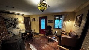 A cozy living room with a fireplace, a dining area, and a sofa. - Quintessential Berkshire Escape - Artist Home, Tucked Away in Nature (Otis)