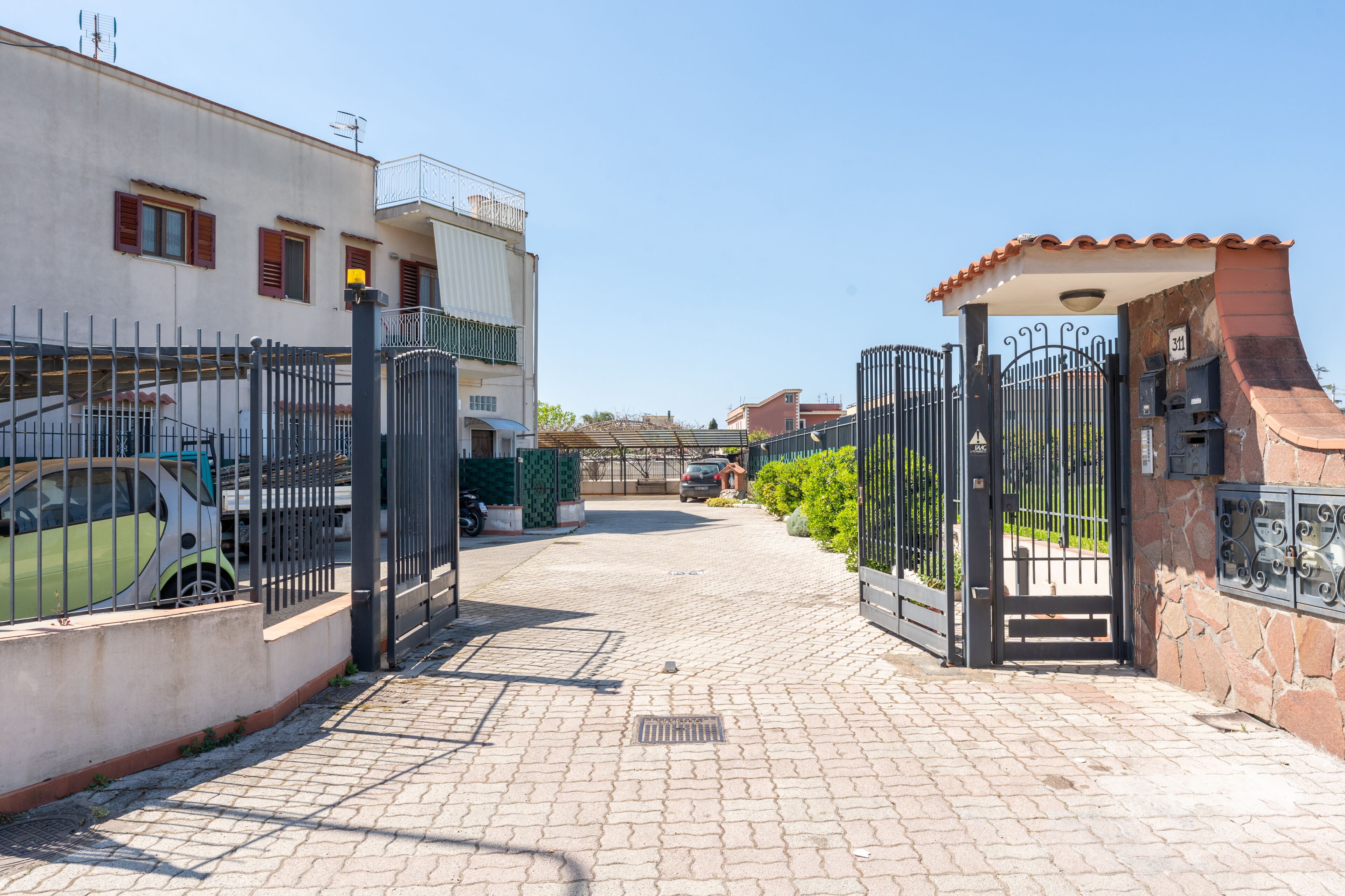 A gated residential area with paved pathways and parked vehicles.