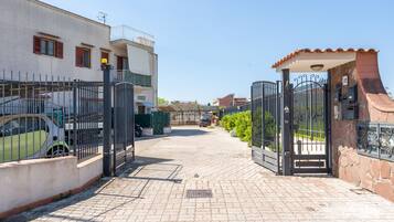 A gated residential area with paved pathways and parked vehicles.