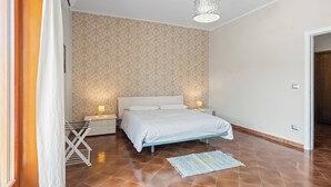 Una camera da letto con un letto, comodini, una lampada, un lampadario e una parete decorata.