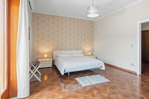 Ein Schlafzimmer mit einem Bett, Nachttischen, einer Lampe, einer Pendelleuchte und einer Wand mit Muster.