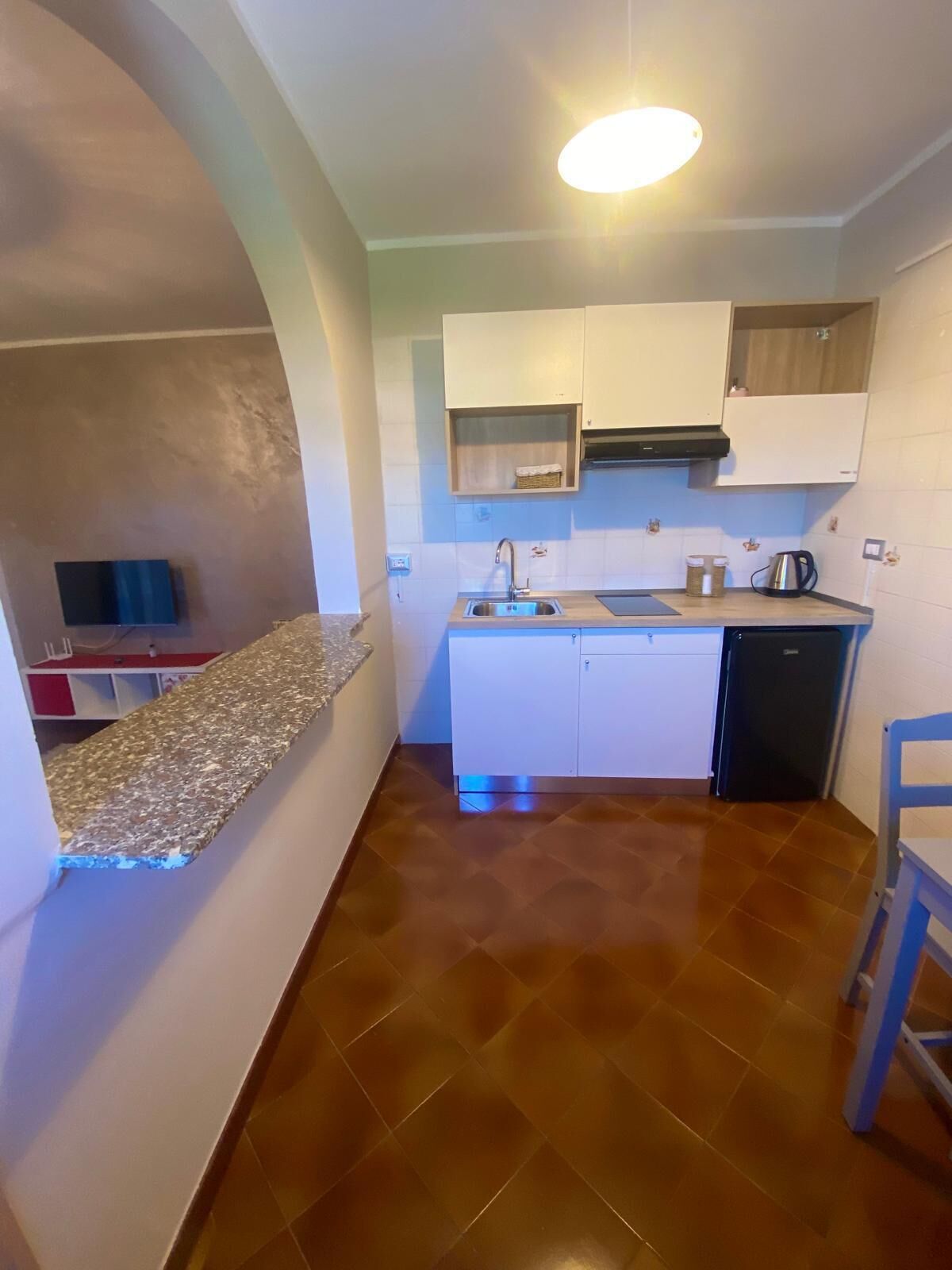A compact kitchen with white cabinets, a stainless steel sink, and a black dishwasher.