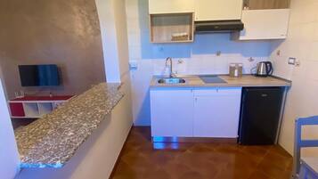 A compact kitchen with white cabinets, a stainless steel sink, and a black dishwasher.
