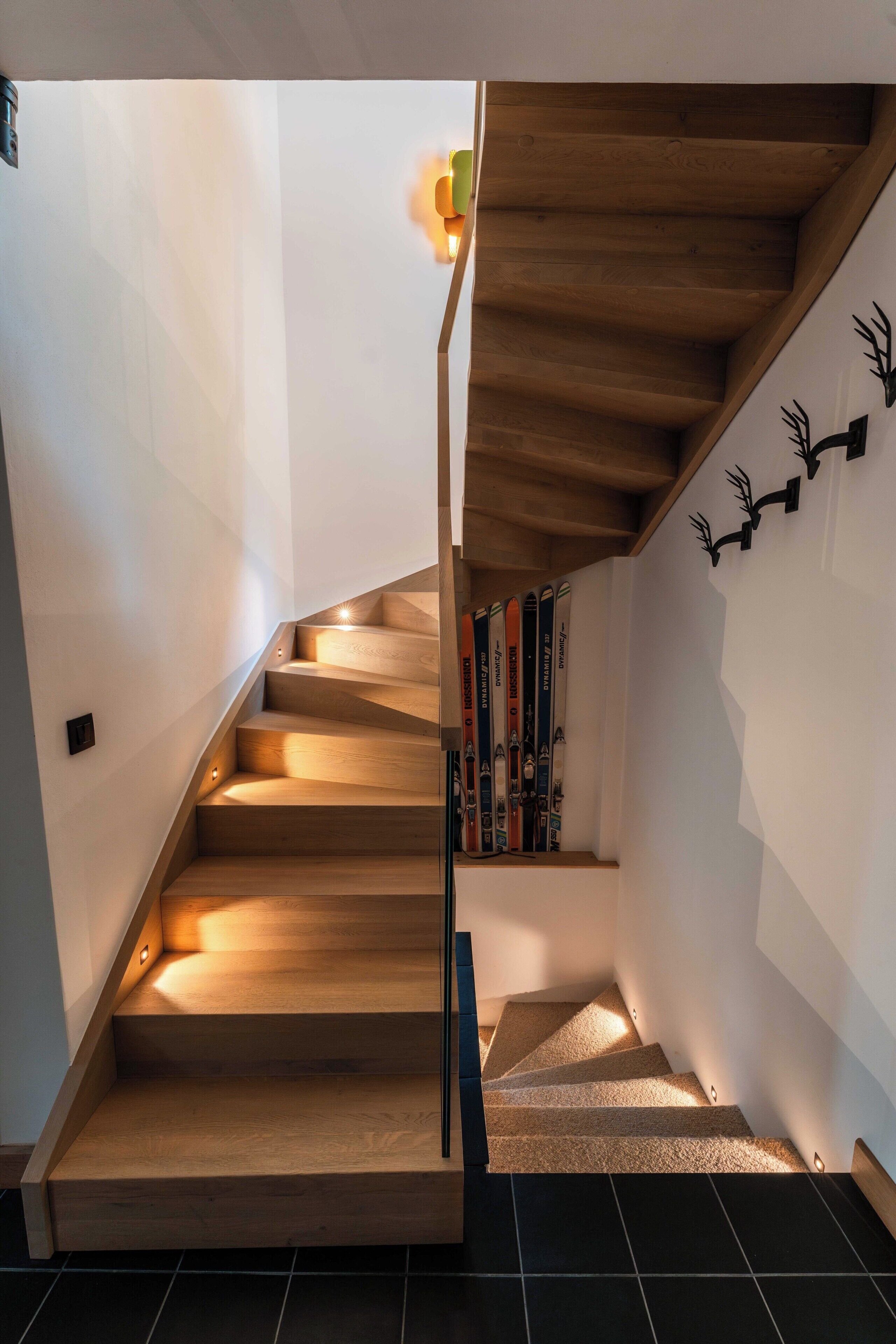 A wooden staircase with a handrail, leading to a landing where books are placed.