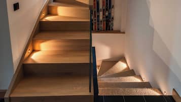 A wooden staircase with a handrail, leading to a landing where books are placed.