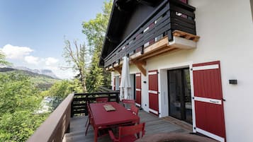 A wooden deck with a table and chairs, overlooking a mountainous landscape.