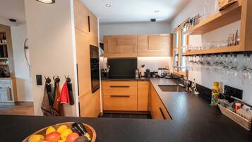 A modern kitchen with wooden cabinets, a black countertop, and a bowl of fruit.