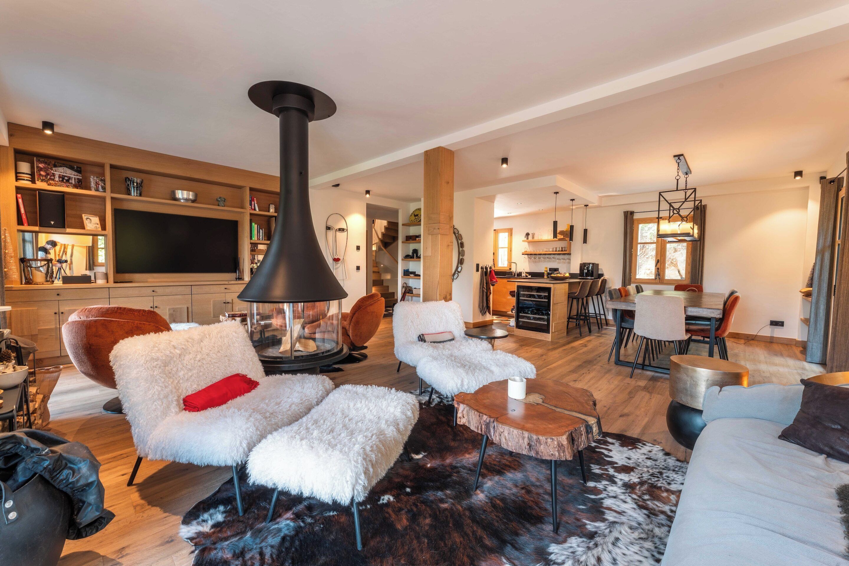 Una sala de estar moderna con chimenea, asientos cómodos, un comedor y una cocina al fondo.