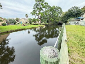 A calm river with a wooden fence and grassy banks, surrounded by trees and residential buildings. -     Your Perfect Beach Escape Sleeps 8 (Panama City Beach)