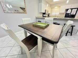 A dining area with a table, chairs, and a kitchen in the background. -     Your Perfect Beach Escape Sleeps 8 (Panama City Beach)