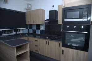 Una cocina moderna con encimera negra, armarios de madera, microondas y estufa.
