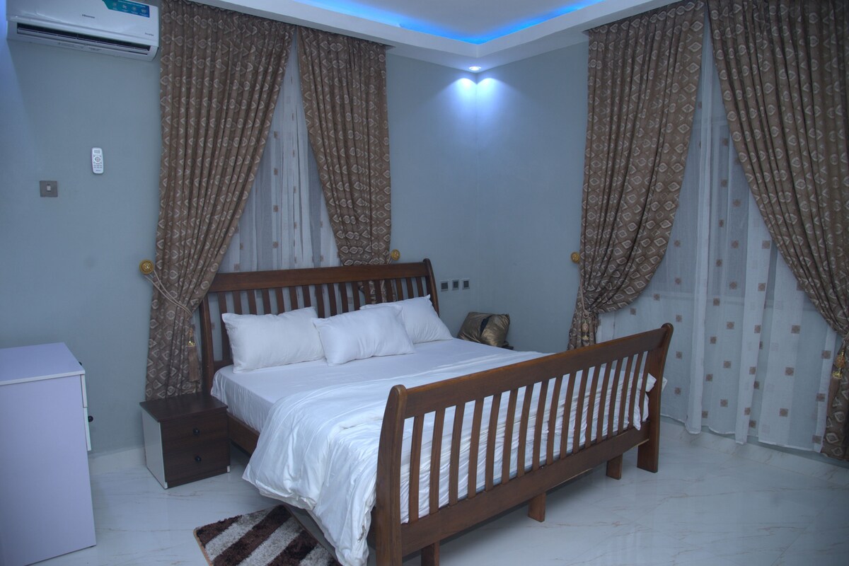 Un dormitorio con una cama de madera, una mesita de noche y un aire acondicionado de pared.