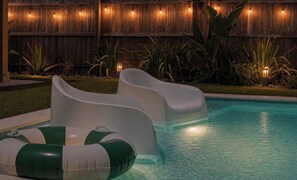 A swimming pool with two slides and inflatable rings. - Be A Nomad | 3BR With Pool (Jacksonville Beach)