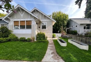 A two-story house with a front yard, a pathway, and a small garden area. - Bright Heritage Home | 2BR | Central | Foodie Hub (Calgary)