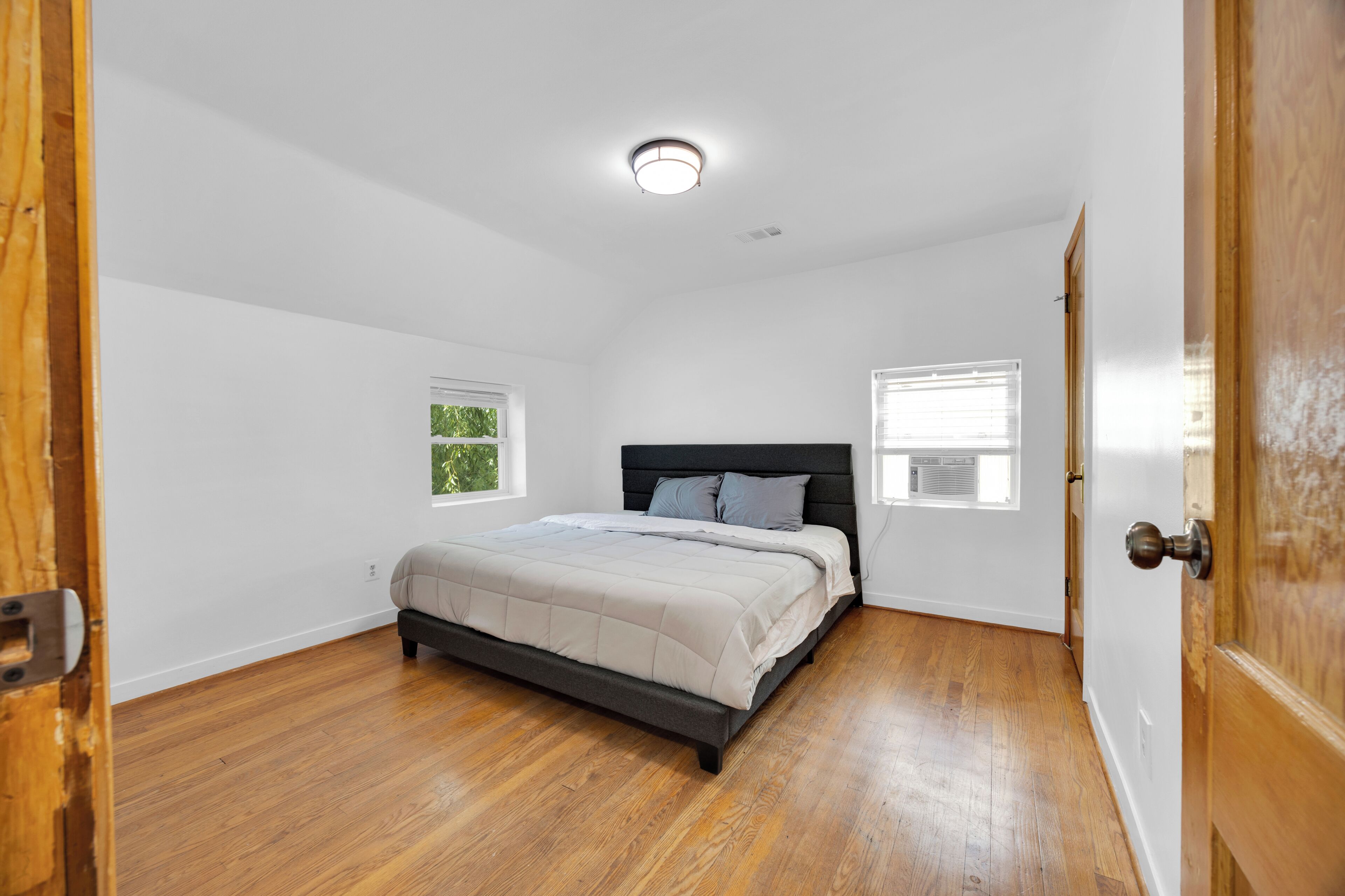 A bedroom with a bed, two windows, and a door.