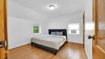 A bedroom with a bed, two windows, and a door.