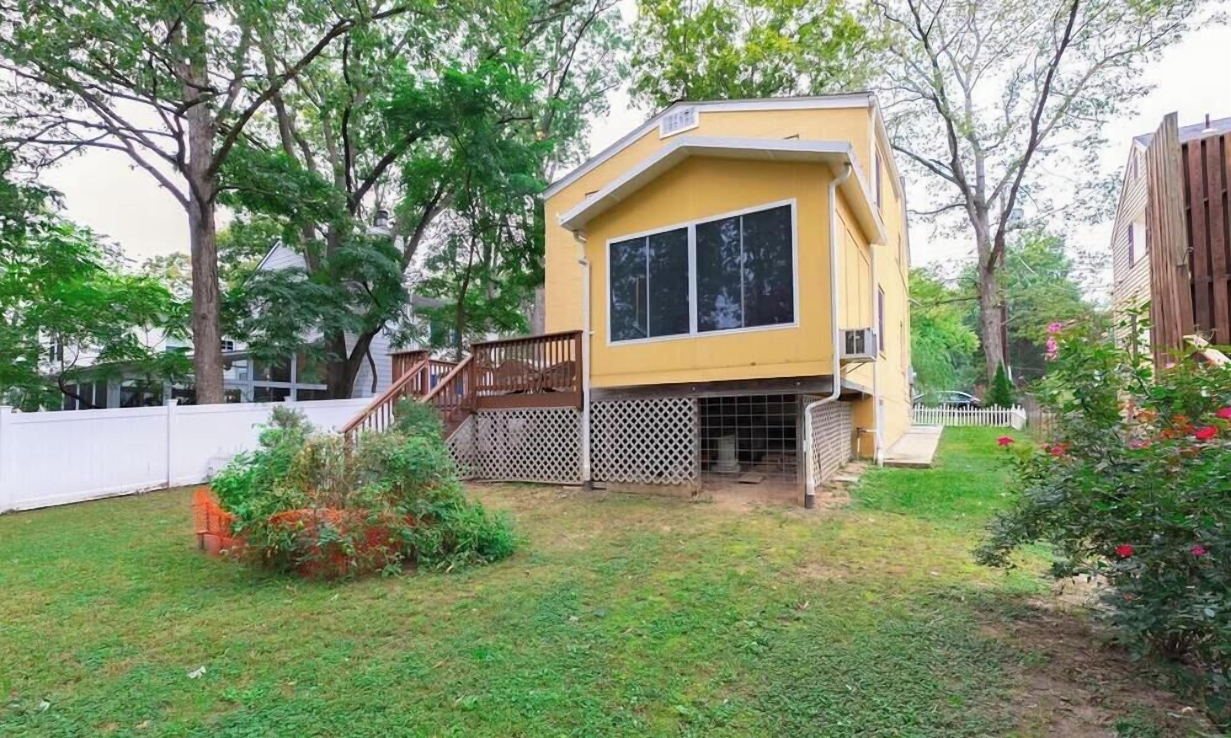 Ein zweistöckiges Haus mit einer Terrasse und einem umzäunten Garten.