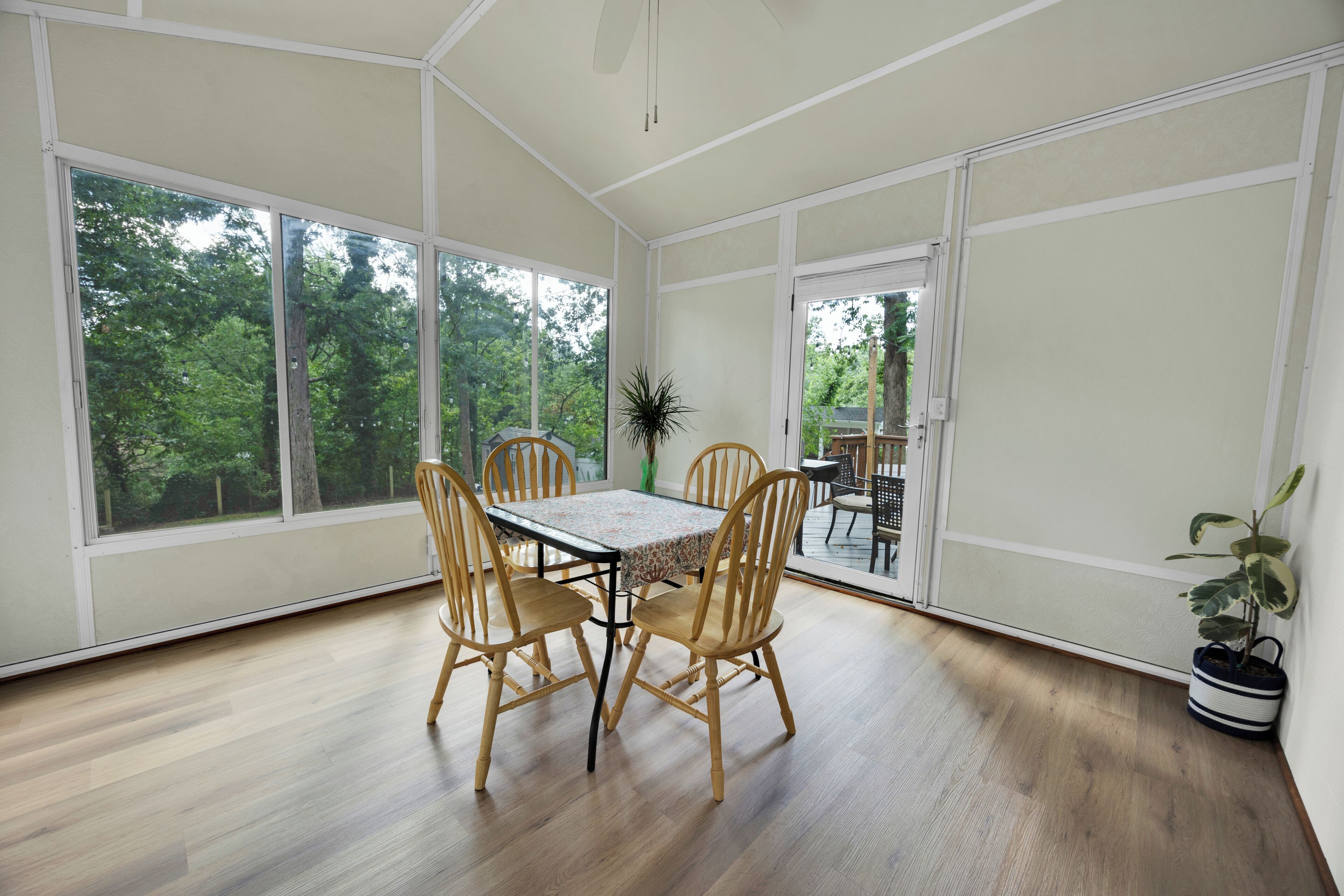 A dining area with a table and chairs, large windows, and a view of trees.