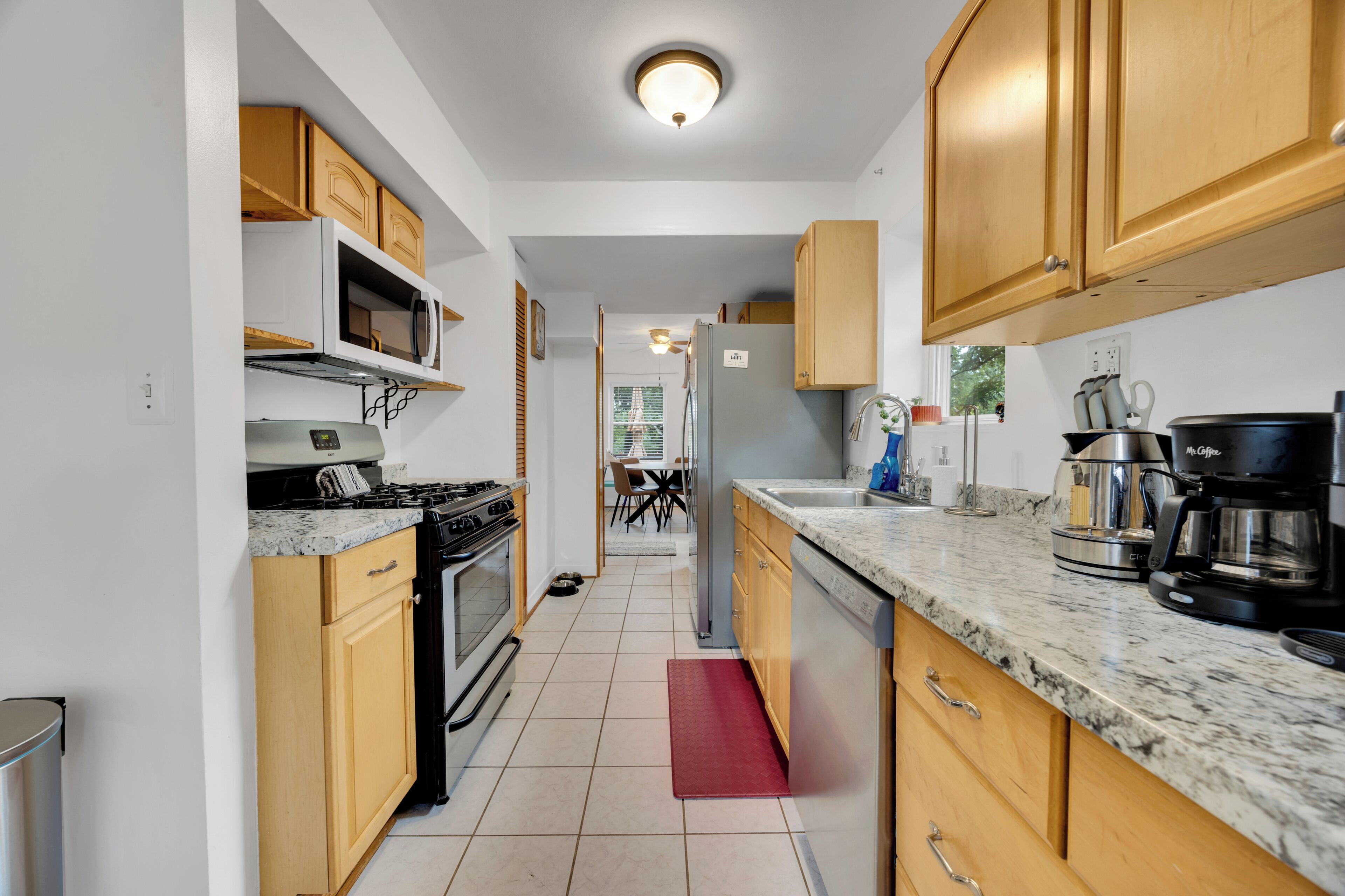 A kitchen with wooden cabinets, a microwave, a stove, and a coffee maker.
