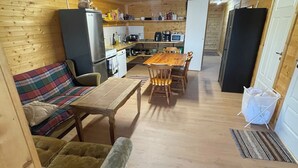 A compact living space with a sofa, a dining table, and a kitchen area. - Amundtorp vandrarhem  (Hastveda)