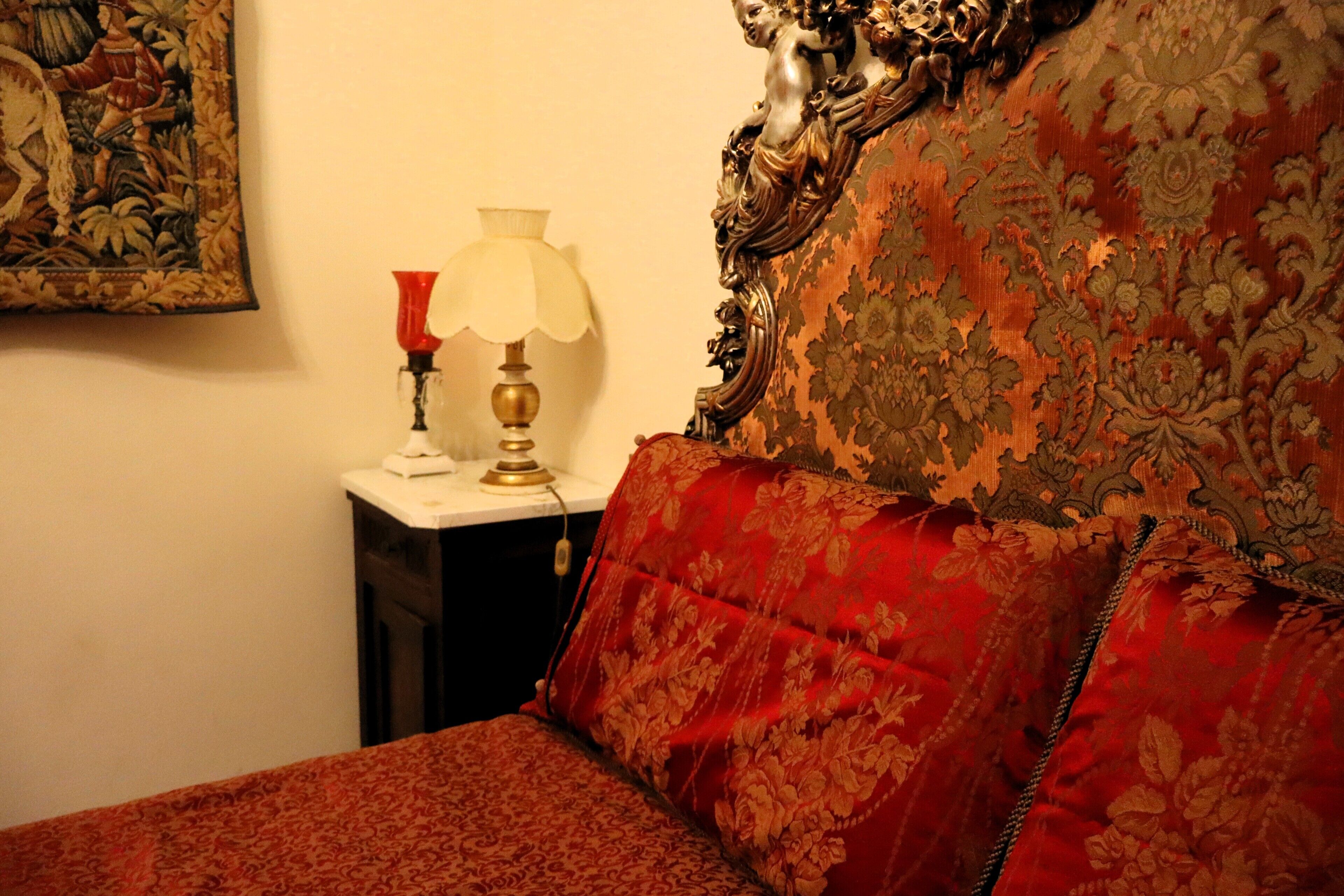 Une chambre avec un lit, une table de chevet, une lampe et un tableau accroché au mur.