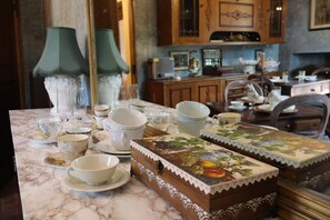 A marble countertop with various tea cups and saucers, a decorative box with a fruit design, and a green lamp.