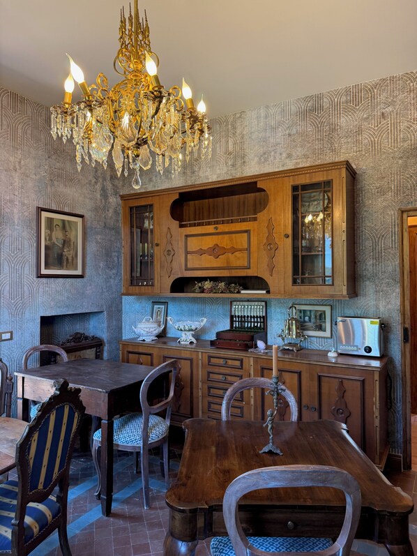 A dining area with a wooden table and chairs, a chandelier, and a cabinet with glass doors.